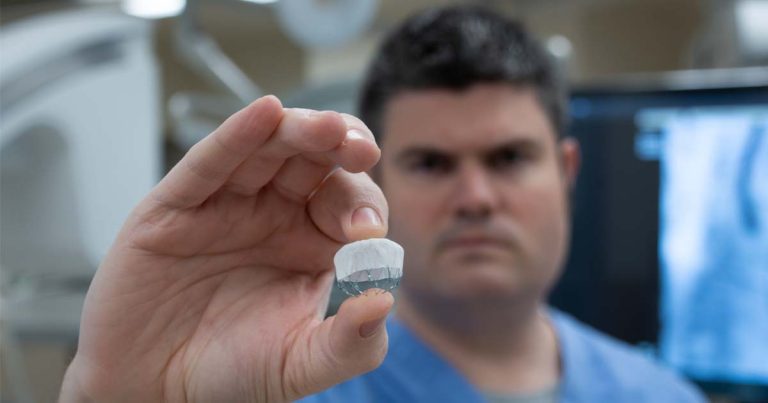 Photo of Dr. Chase Reynolds holding a Watchman Device