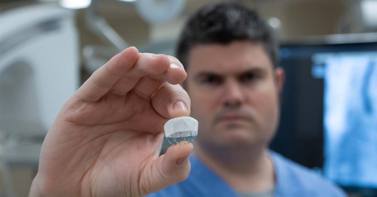 Photo of Dr. Chase Reynolds holding a Watchman Device