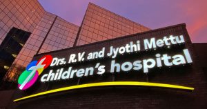 Image of the Mettu Center Children's hospital sign against the building and sky.