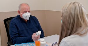 Photo of Barry Estep consulting with a pharmacist at PMC's Speciality Pharmacy
