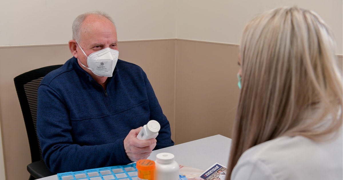 Photo of Barry Estep consulting with a pharmacist at PMC's Speciality Pharmacy